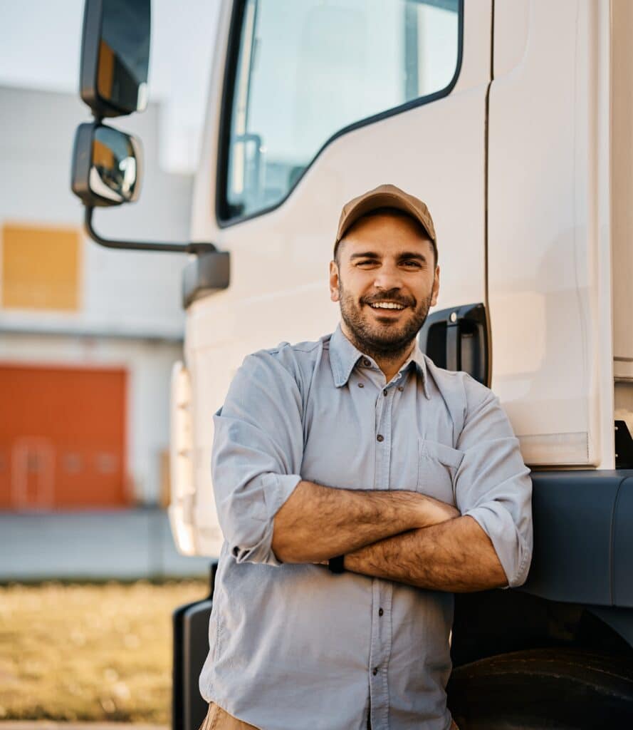 Truck driver leaning against his truck after having a toolbox talk with his trucking team about their fleet safety plan.