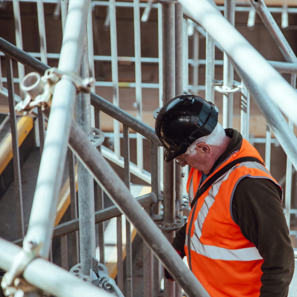 Construction worker with hard hat and vest on a construction scaffolding.
